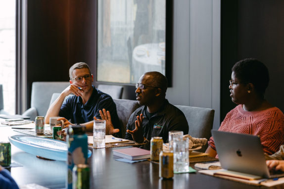 Three people sit at a desk.